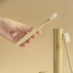 Mano sosteniendo un cepillo de dientes de bambú